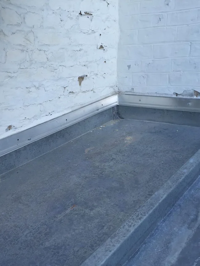 Toit plat avec relevé d'étanchéité contre un mur de façade