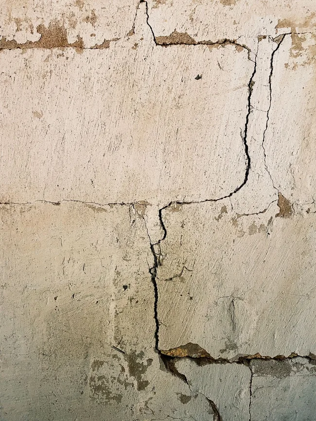 Mur de maison fissuré avec un enduit abîmé